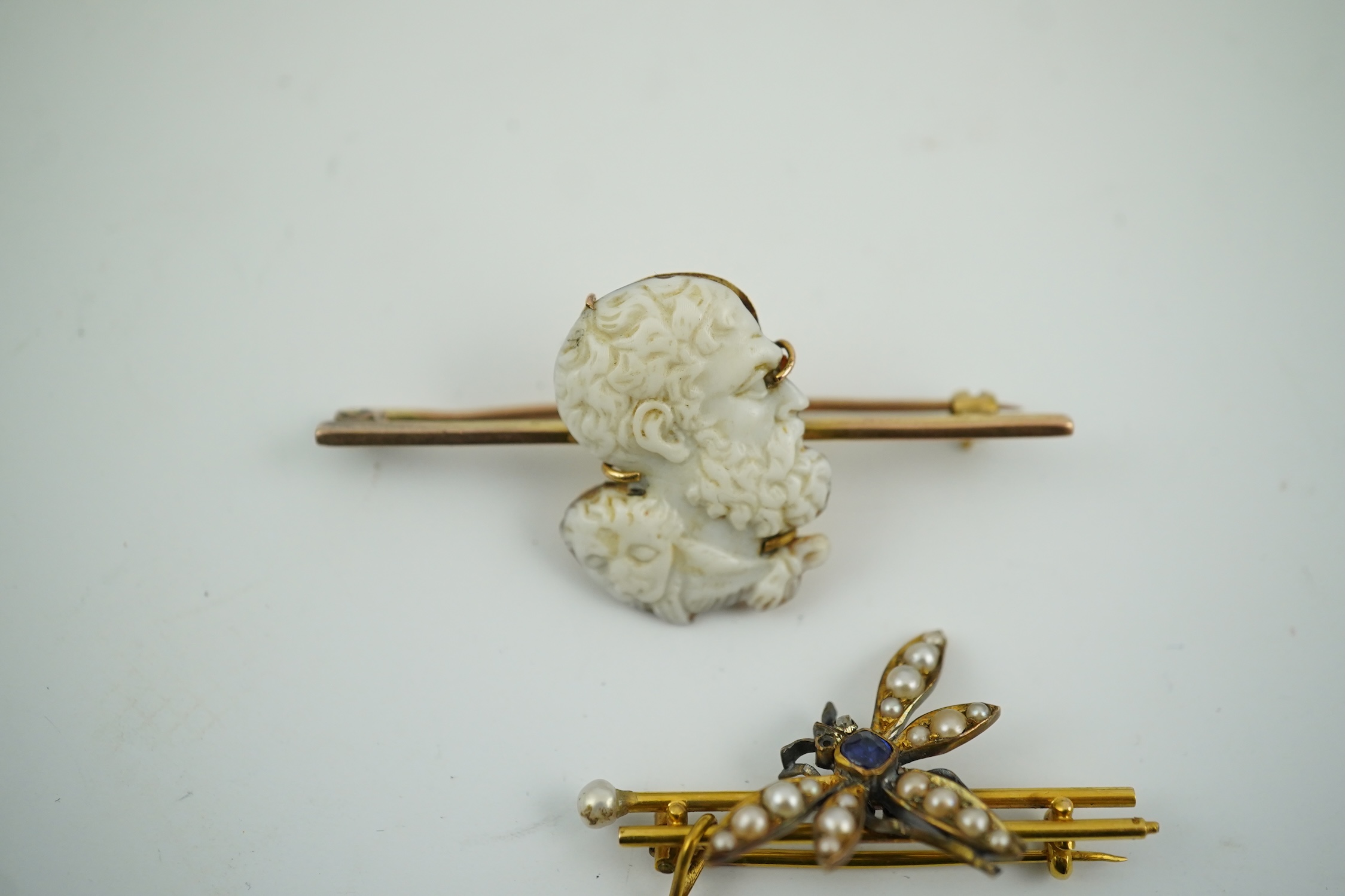 An Edwardian 15ct mounted cameo shell bar brooch, 49mm, together with a yellow metal, sapphire and split pearl cluster set dragonfly bar brooch, 11 grams. Condition - fair